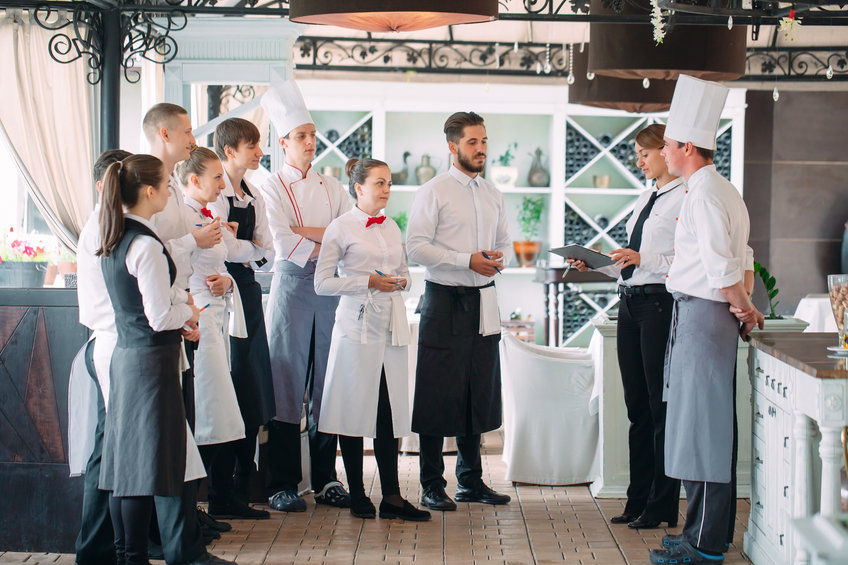 Directeur du restaurant et son personnel en terrasse. interagissant avec le chef de cuisine dans le restaurant.